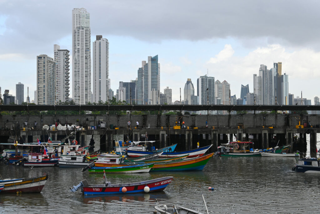 Colourful fisher boats in the front, pier and city skyline in the background 