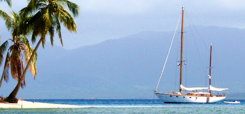 Sail boat next to an island with a white sand beach