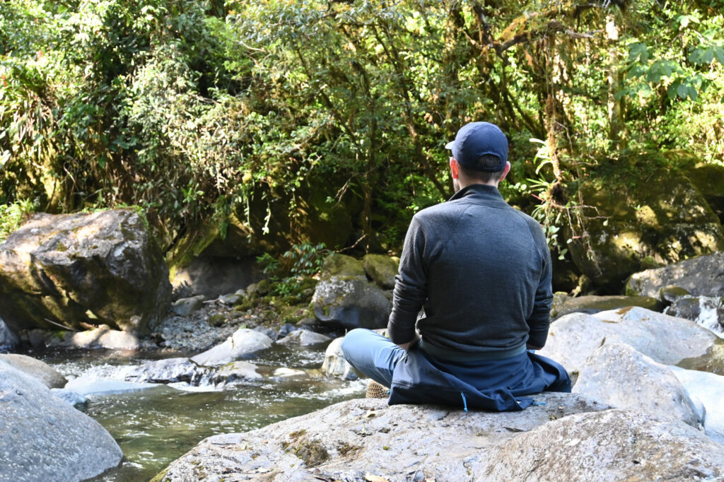 Person meditating on a stone next to a river