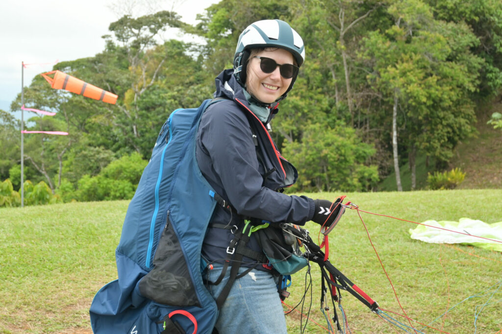 Woman with paragliding gear, sunglasses and helmet similing