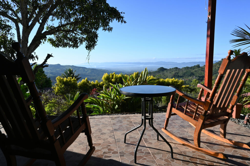 Chairs and table in the foreground on a terrace looking at a green valley