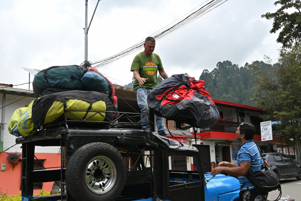 Two people loading paragliding equipment onto a roof of a jeep