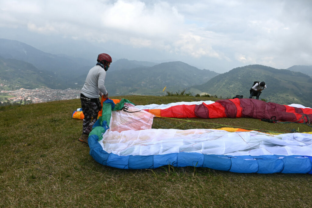 Two tandem paragliders with mountains in the background