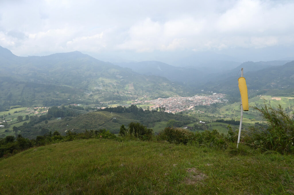 Windsock on a grass field looking down at a town in the valley