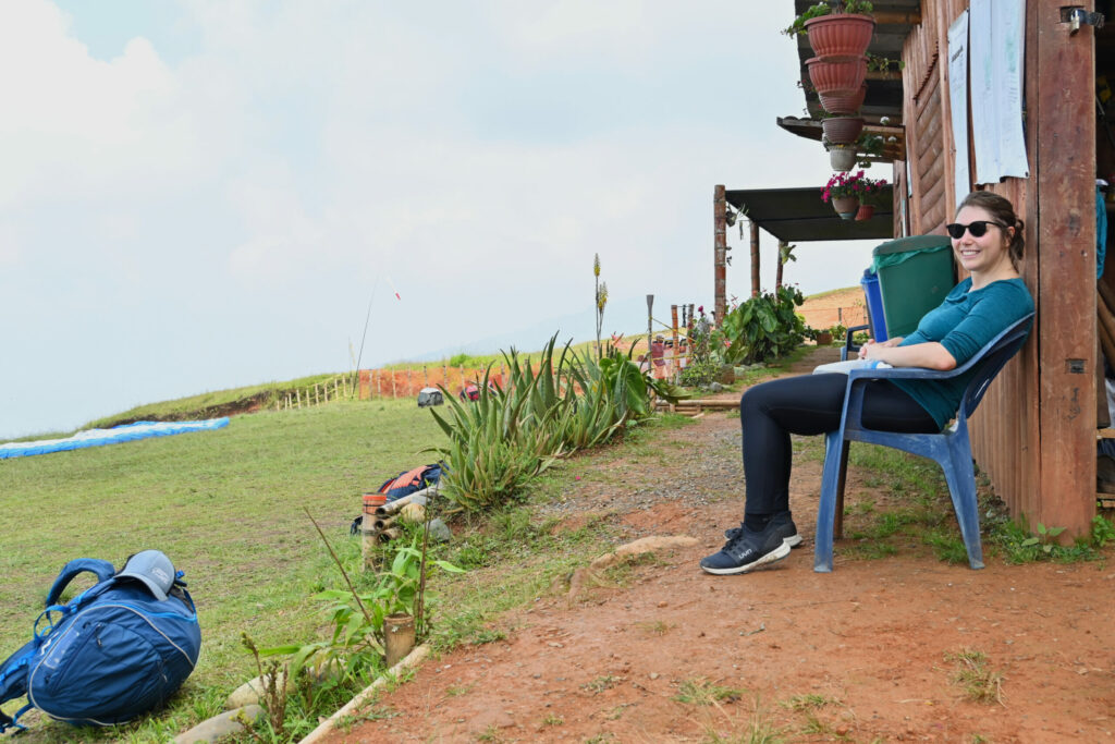 Building with woman sitting in fron of it and green field on the left