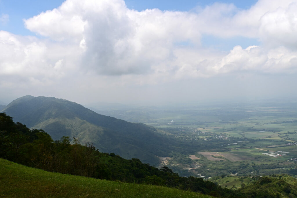 Green ridges to the left, valley to the right and white clouds above