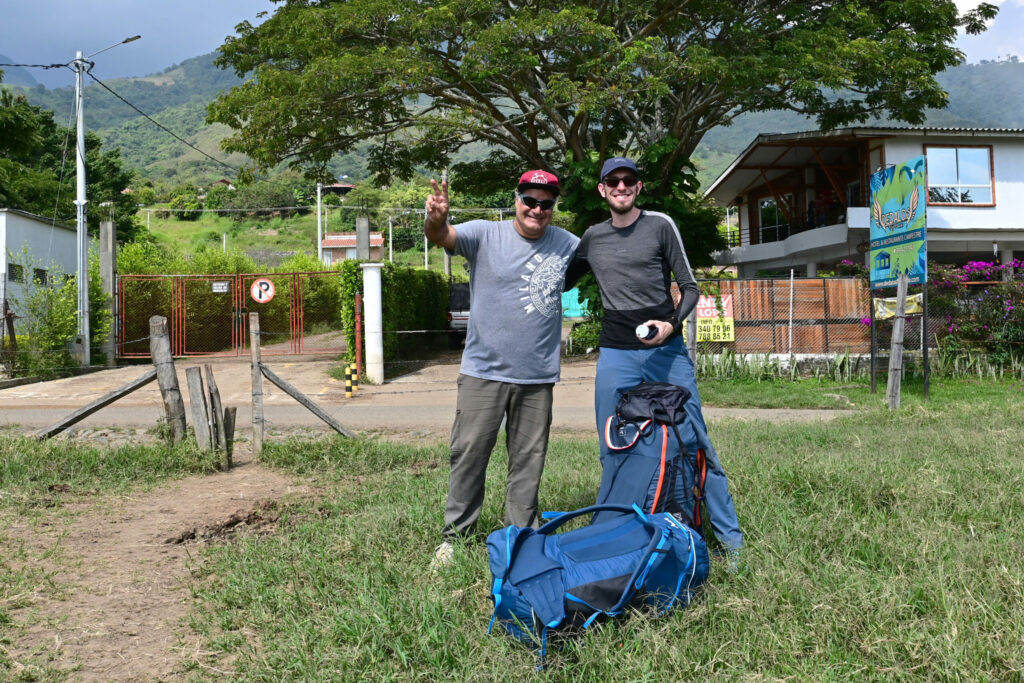 Two man smiling into the camera with paragliding equipment below their feet