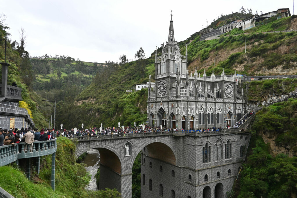 Huge church with a bridge in a narrow valley with crowds of people in front of it