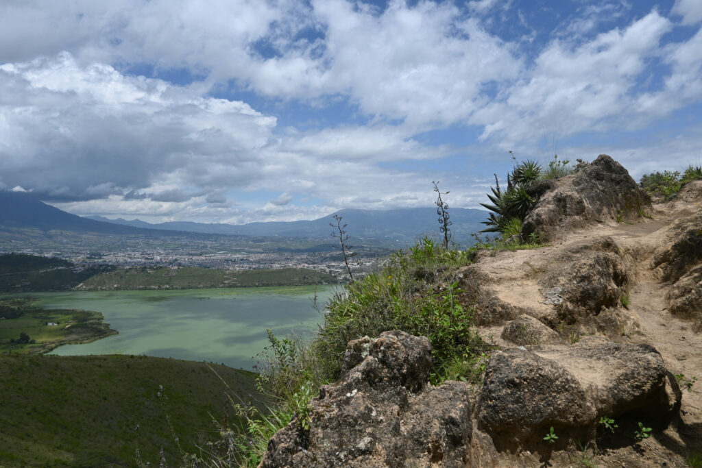 A small hiking path, in the background a lake and a city