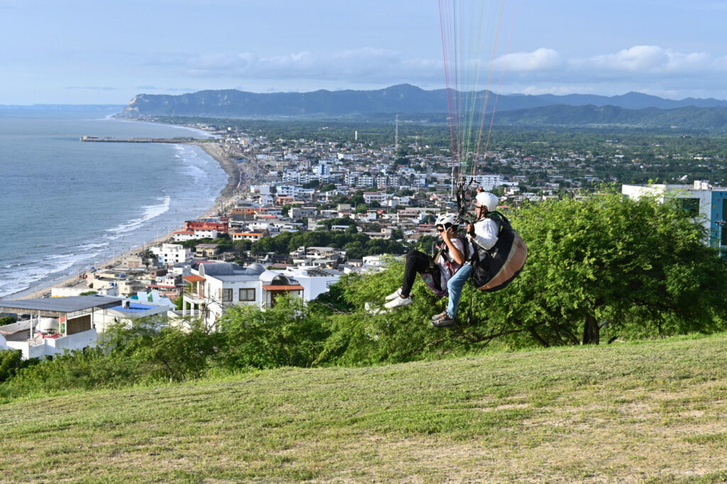 A paraglider taking off, in the background a cost line and a village