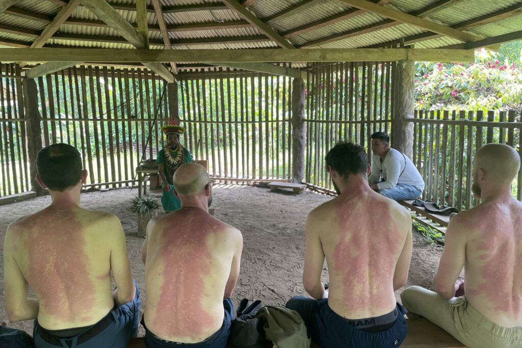 Four people with red backs sitting in front of a Shaman