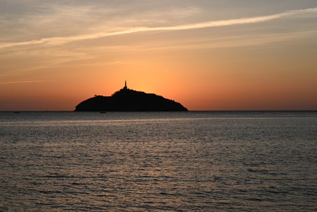 the sun is going down behind an island in the sea